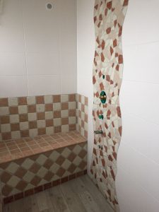 Fliesenarbeiten an Badewanne mit rot-beige Mosaikfliesen – Detail einer Badsanierung