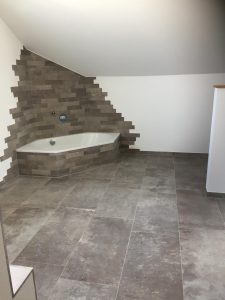 Eckbadewanne in grauer Fliesen-Optik